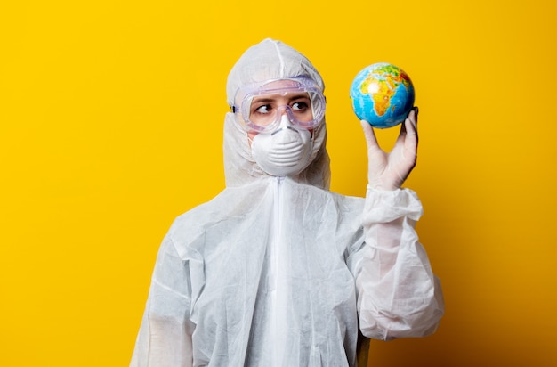 Medic in protection suit and mask hold Earth globe