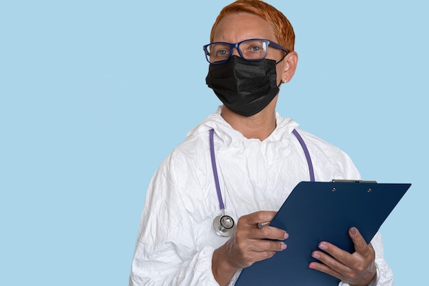 A medic in a protective suit holds a tablet with a form for describing the diagnosis