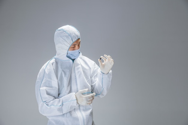 Medic in white hazmat protective suit prepares a pills for prevention against pneumonia