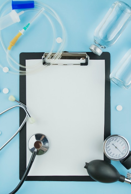 Medical background. White paper on clipboard with pen, stethoscope, dropper system, solution on a blue background. The medicine. Copy space. Flat lay.