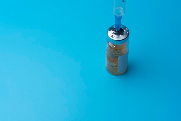 Medical bottle with syringe on blue background