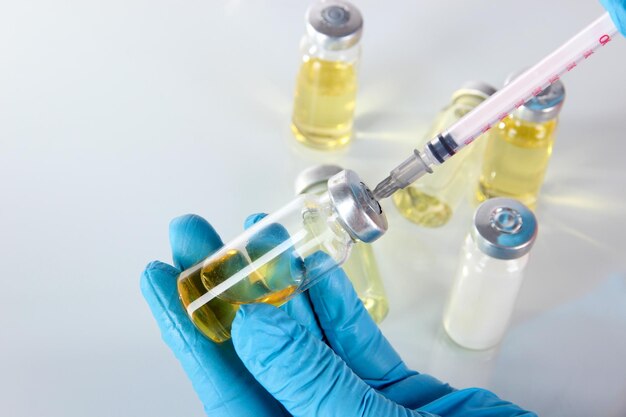 Medical bottles and syringe in hand on gray background