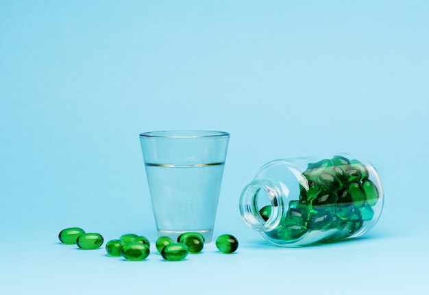 Medical capsules pills and glass water on a blue background