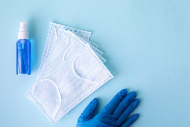 Medical concept on a blue background. Means of protection against the virus: medical mask, antiseptics, hand hygiene products, sanitizers. Medical gloves. Copy space