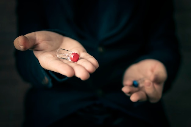 Medical concept. The choice of medication by analogy with the matrix. Choosing the best vaccine. Man holds a blue and red ampoule in his hands. the seller offers drugs