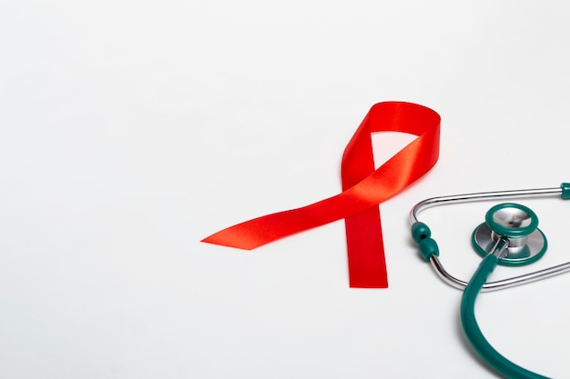 Photo medical concept december world aids day. red ribbon and green medical stethoscope on a white background. safe sex concept. close-up