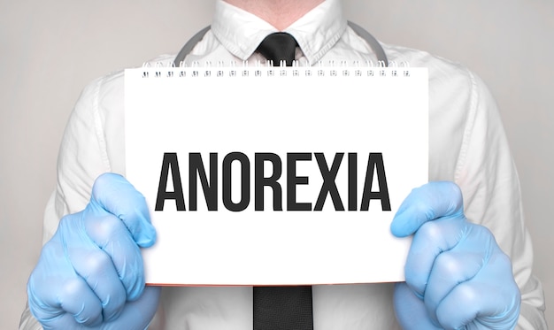 Medical concept. Doctor is writing the word anorexia on white paper notepad