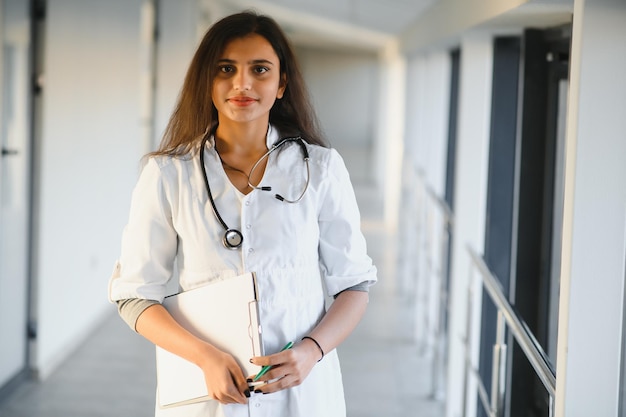 Medical concept of Indian beautiful female doctor in white coat with stethoscope, waist up. Medical student.