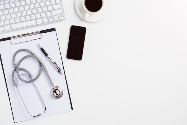 Medical desk with stethoscope,heart,pen,laptop,mouse and x-ray film on white desk.Top view