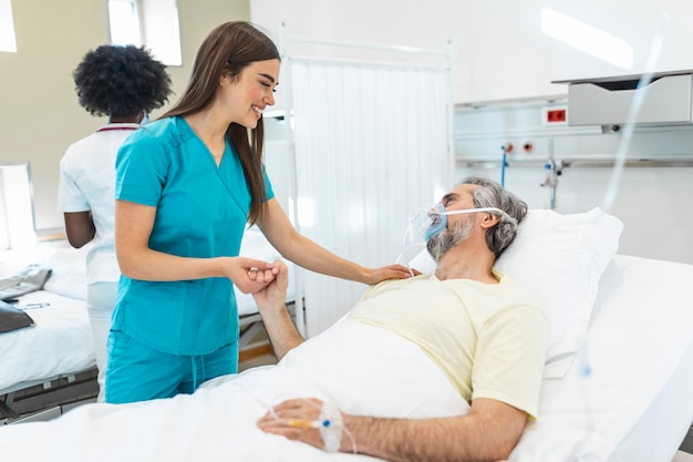 Medical doctor or nurse holding senior patients hands and comforting him