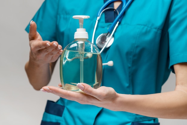 Medical doctor nurse wearing protective mask holding sanitizing spray or gel or liquid soap