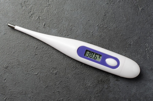 Medical electronic thermometer on a black background High temperature The concept of diagnosis of diseases