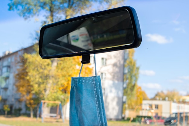 Medical mask hangs on rearview mirror in car