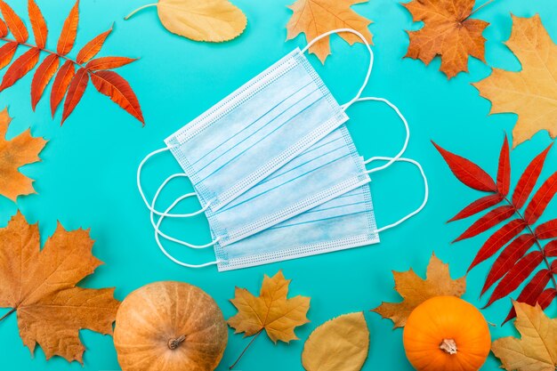 Medical mask between maple leaves isolated