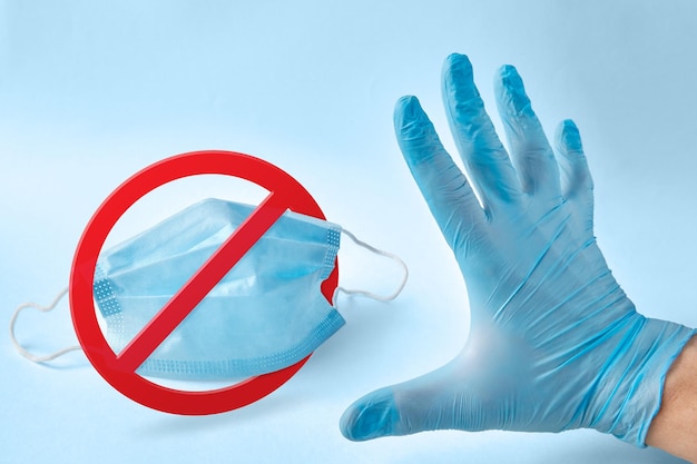 Medical mask under a prohibition sign and a hand in a latex protective glove with a Stop gesture