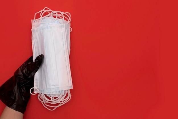 Medical mask and sanitizer on a red background. Coronavirus prevention medical surgical mask and hand sanitizer for hand hygiene coronavirus protection. Crisis due to coronavirus COVID-19 quarantine.