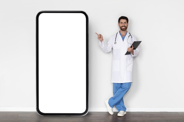 Medical Offer Male Doctor In Uniform Pointing Finger At Big Blank Smartphone