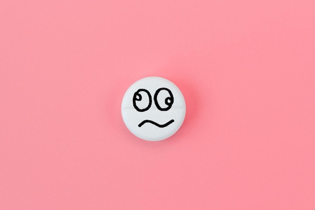 Medical pill with a crazy smiley face on a pink background Drug concept