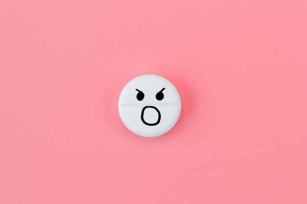 Medical pill with screaming emoji on pink background