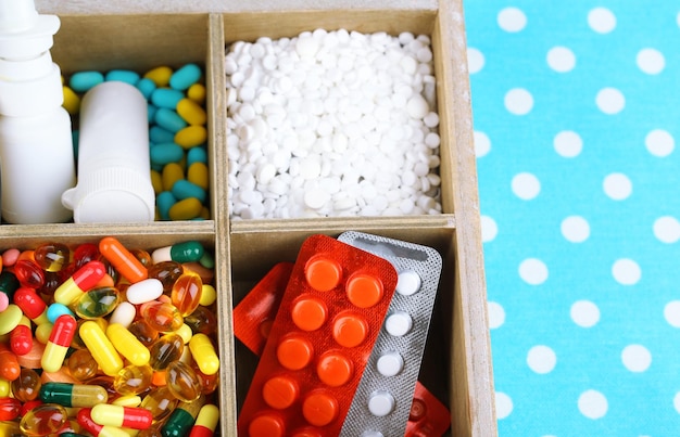 Medical pills ampules in wooden box on color background