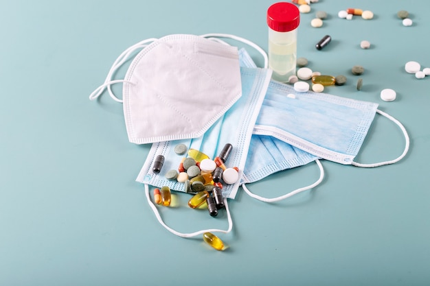 Medical pills and capsules with medical masks over blue texture background. COVID-19. Top view. Copy space