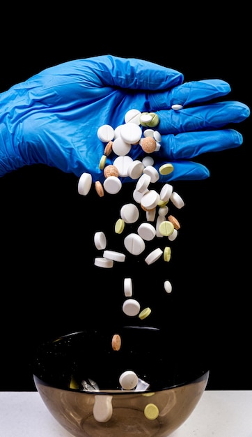 Medical pills on an isolated black background with reflection dropped from hand