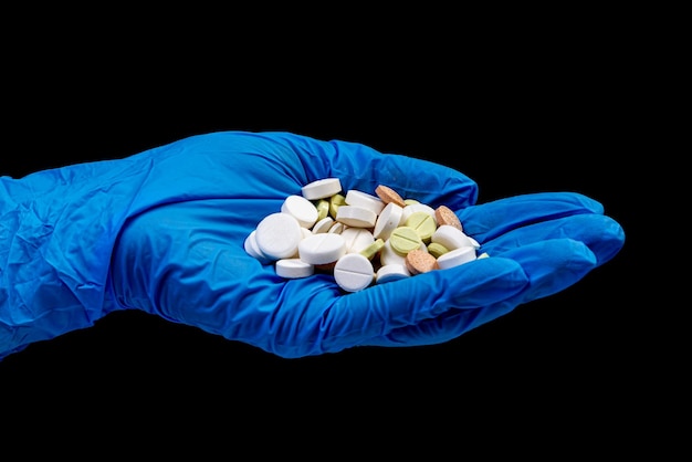 Medical pills on isolated black background with reflection in hand