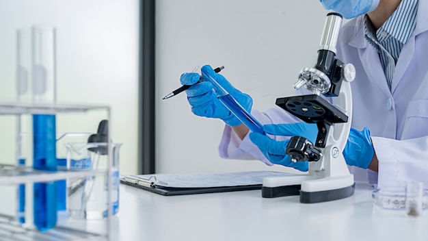 Medical or scientific researcher or man doctor looking at a test tube of clear solution in a laboratory