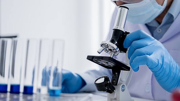 Medical or scientific researcher or man doctor looking at a test tube of clear solution in a laboratory