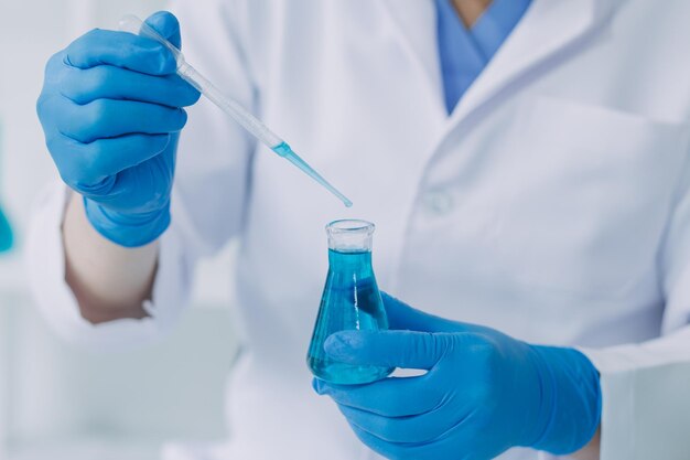 Medical or scientific researcher researching and experimenting Multicolored solution vial and microscope In the laboratory or in the laboratory by wearing blue gloves and white clothing completely