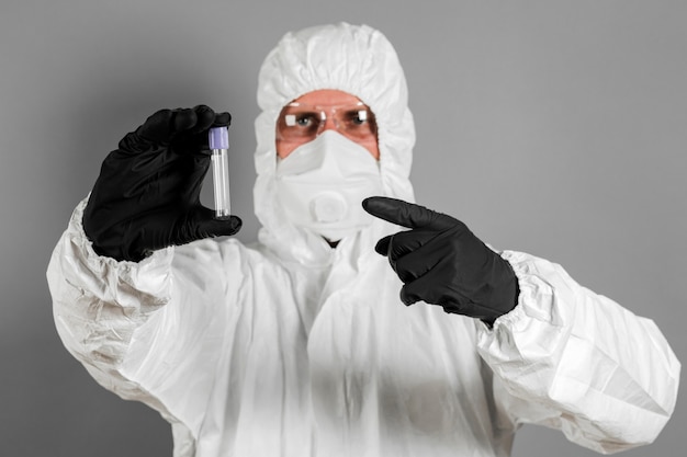 A medical scientist or a policeman wearing protective clothing holds a plastic tube in his hand. The concept of health and crime.