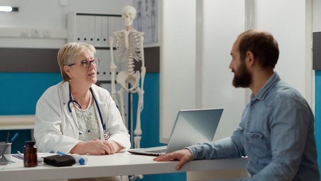 Medical specialist having conversation with patient at appointment in cabinet. Discussing about disease diagnosis and prescription medicine, checkup visit health care examination.