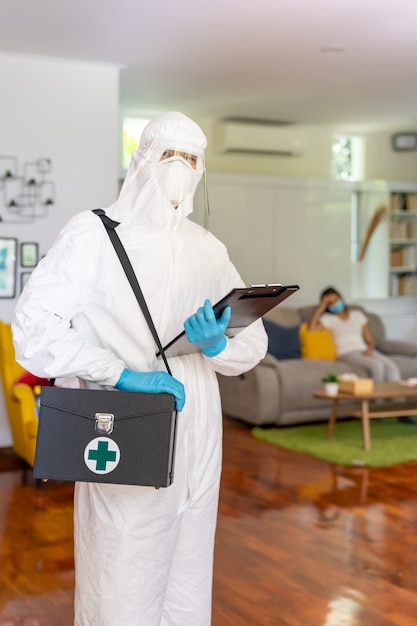 Medical staff in personal protective equipment PPE suit with background of asian woman with face mask  Delivery coronavirus covid test at home concept