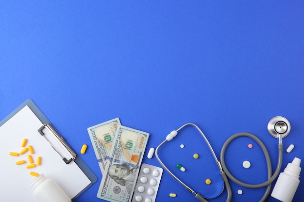 Medical stethoscope and money on a colored background top view closeup