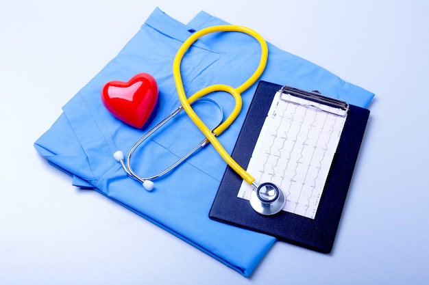 Medical stethoscope, patient medical history list, RX prescription, red heart and blue doctor uniform closeup.