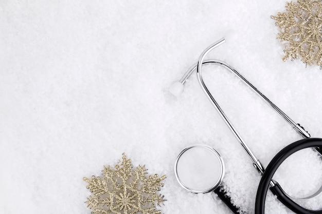 Medical stethoscope on a snowy background near snowflakes