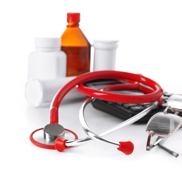 Medical stethoscope with bottles of pills and calculator isolated on white