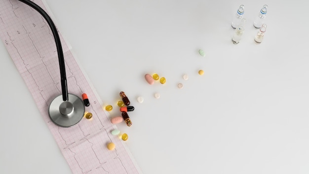 Medical stethoscope with pills and cardiogram on a light background. top view