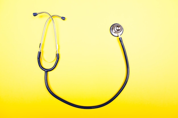 Medical stethoscope on yellow background in studio photo. Top vi