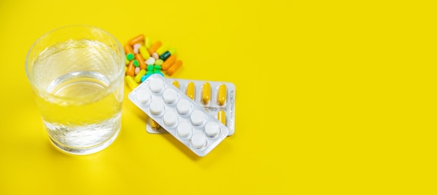 Medical supplies on a yellow background, pills water treatment mask virus. Selective focus