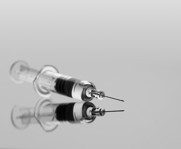 Medical syringe with vaccine on grey background