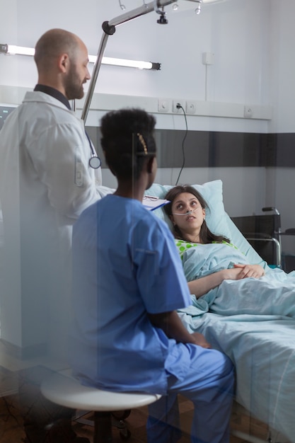 Medical team monitoring sick woman explaining sickness symptom examining medical recovery in hospital ward