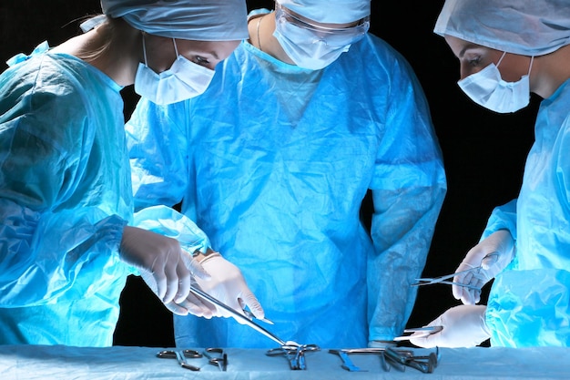 Medical team performing operation. Group of surgeon at work in operating theatre toned in blue.