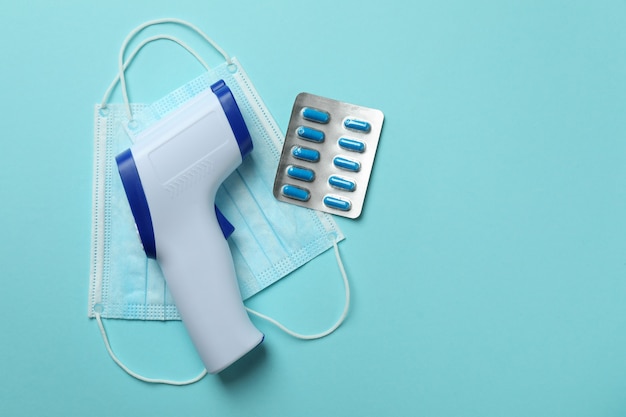 Medical tools and thermometer gun on blue