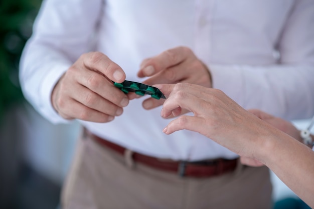 Medical treatment. Close-up of male and female hands holding pill blister pack