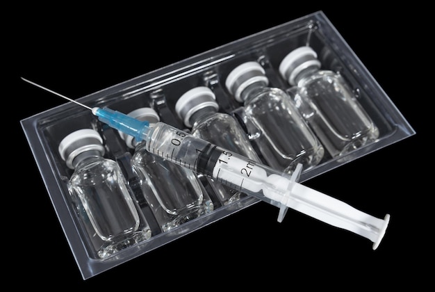 Medical vials with vaccine in plastic container on a black background