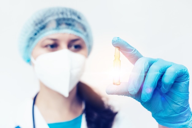 A medical woman holds an ampoule with a vaccine or medicine in her hand and looks at it A new vaccine for covid 19