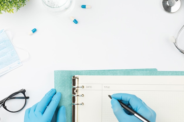 Medical worker at table write in notebook top view