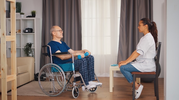 Medical worker with old patient in wheelchair doing physiotherapy. Disabled handicapped old person with social worker in recovery support therapy physiotherapy healthcare system nursing retirement hom