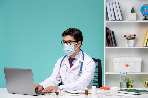 Medical working on computer remotely serious cute smart doctor in lab coat typing on laptop